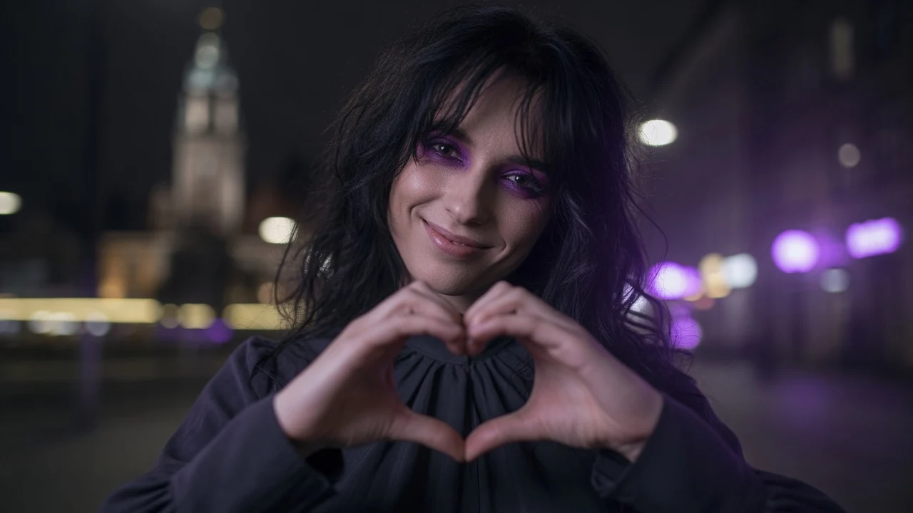 A transsexual woman in Warsaw at night shows a heart symbol with her hands against the background of the Palace of Culture and smiles flirtatiously